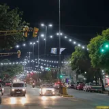 Tránsito nocturno en la avenida Facundo Zuviría, iluminada con guirnaldas de luces y banderas celestes y blancas.