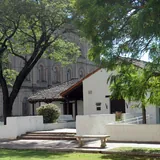 Fachada blanca de estilo colonial del Museo Histórico Provincial Brigadier Estanislao López en Santa Fe, con techos de tejas, rodeada de frondosos árboles verdes.