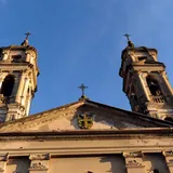 Plano contrapicado de las dos altas torres campanario y el frontón superior del histórico Convento de Santo Domingo en Santa Fe, recortados contra un cielo azul claro
